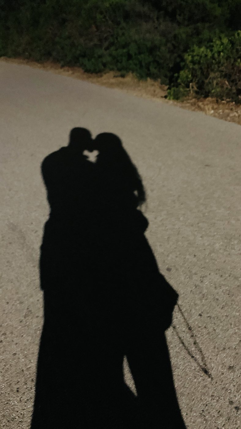 Two shadows sharing a kiss on a sunlit path